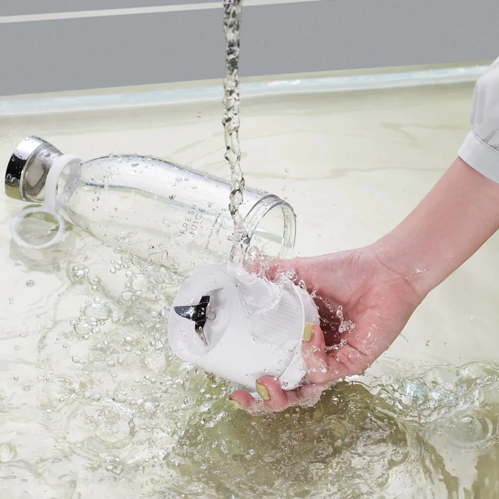 A Fresh Juice White portable blender being washed under water.