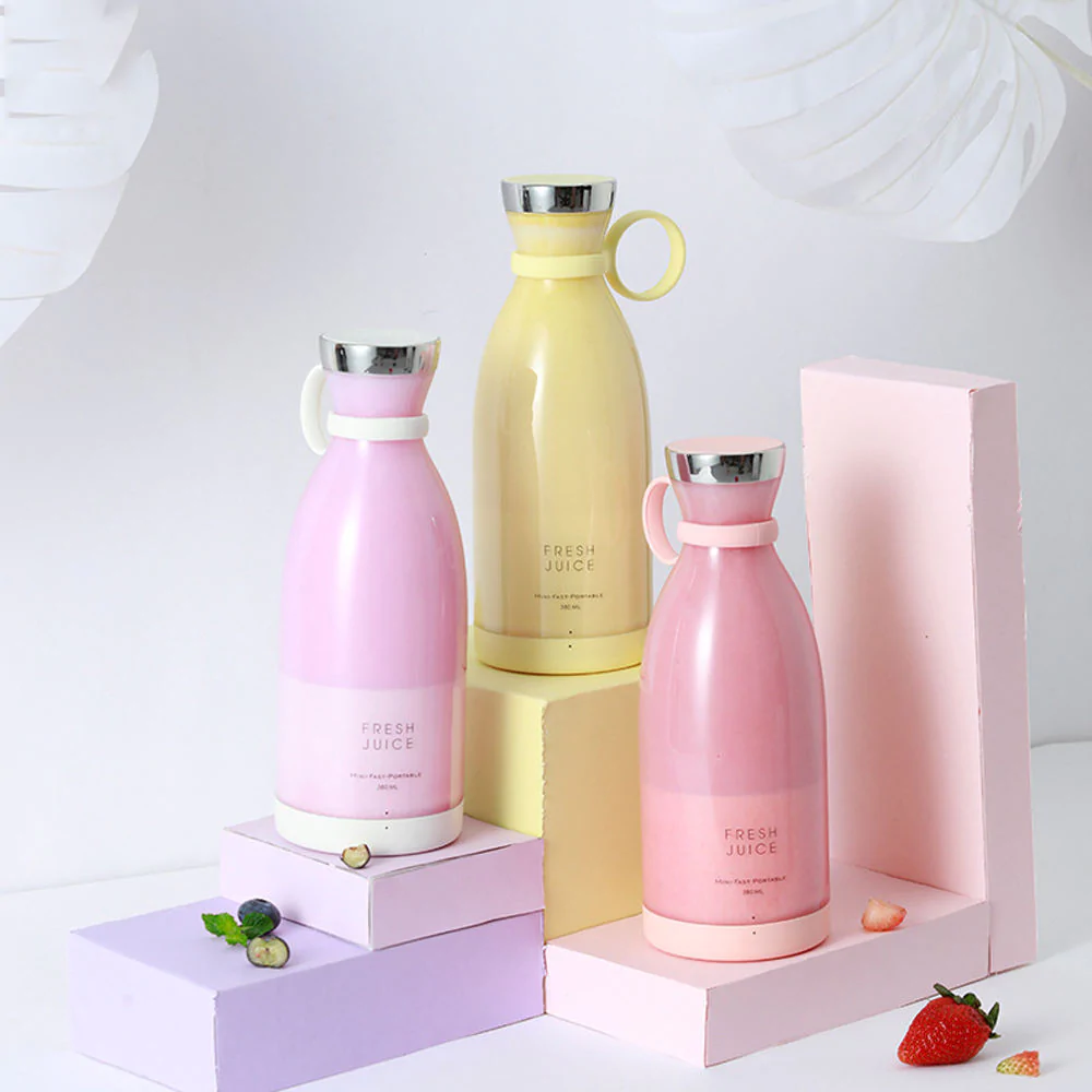 Three Fresh Juice blenders in pink, white and yellow filled with pink, purple and yellow smoothies on a white background.